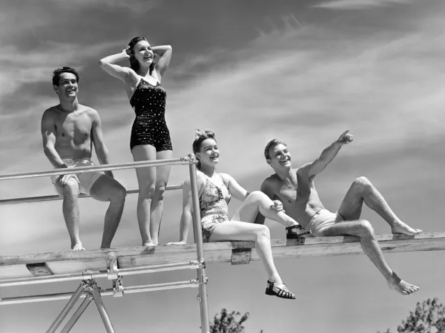 Vintage photo of young people standing on diving board in swimwear