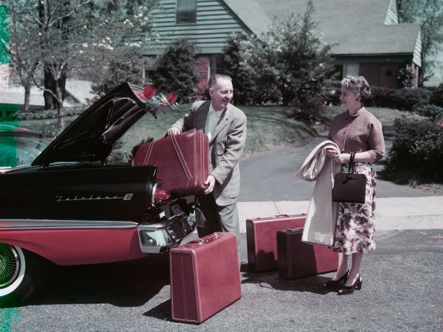 Man and woman packing trunks into car in 1950s