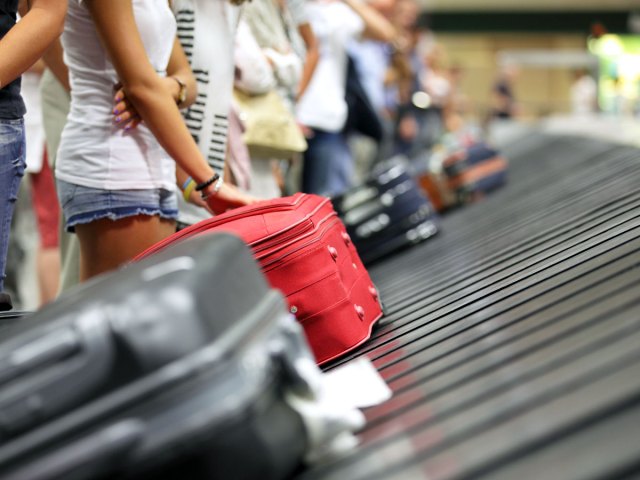 Passengers standing at baggage claim with bags on carousel