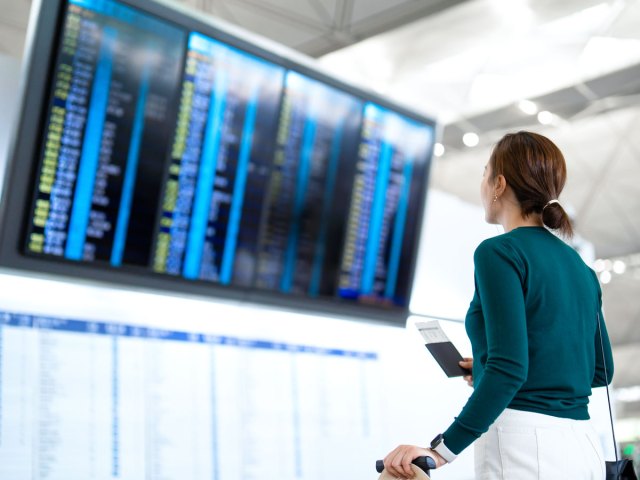 Traveler looking at flight status board at airport