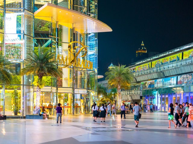 People walking in front of modern shopping mall at night in Bangkok, Thailand