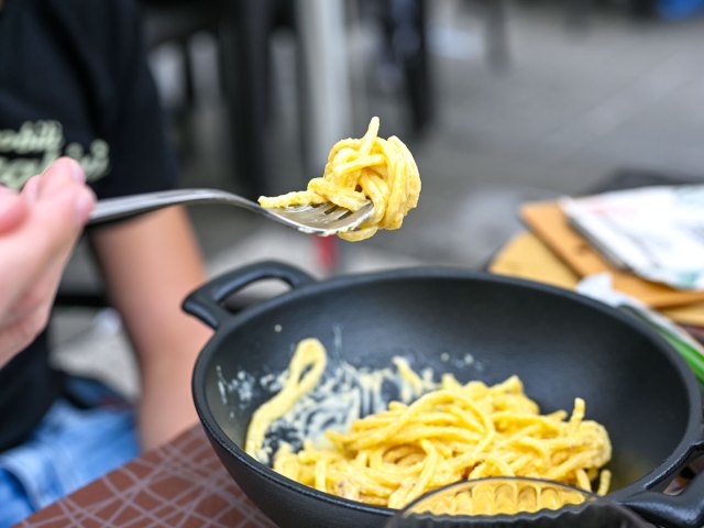 Person taking forkful of pasta from pot