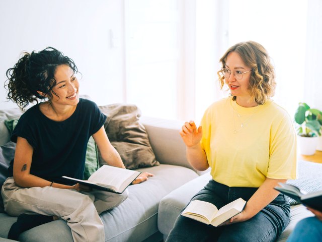 Two people holding books and discussing