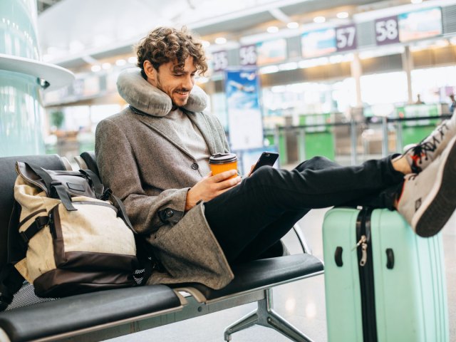 Traveler sitting in airport with neck pillow