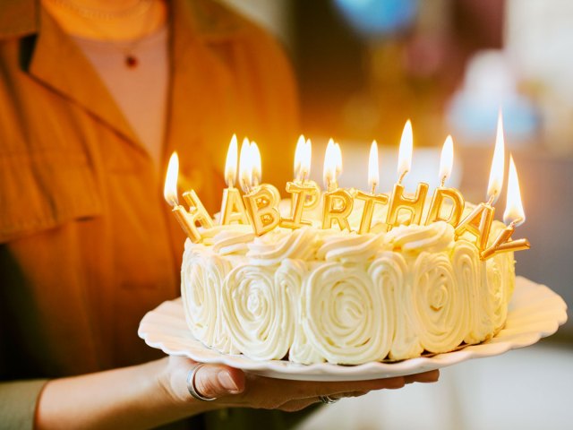 Person holding birthday cake lit with candles