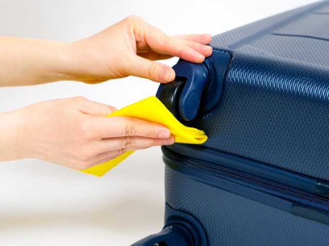 Person wiping down wheels of suitcase