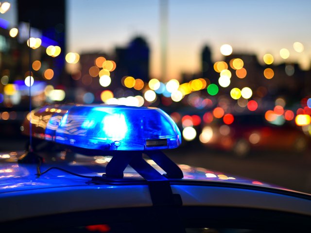 Lights flashing on police car with city background blurred