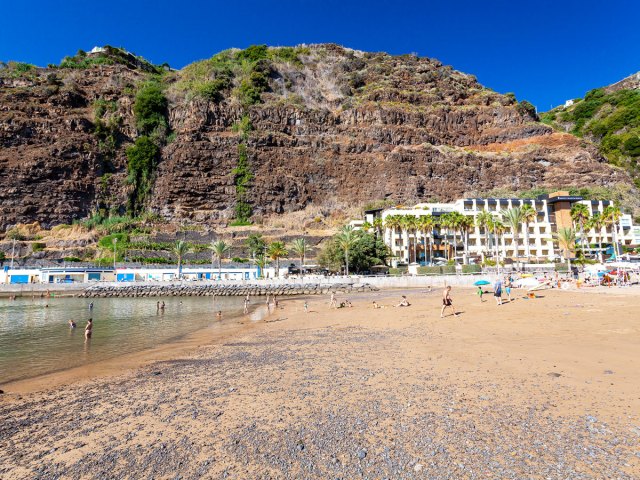 Sandy beach of Calheta, Madeira, framed by volcanic hills