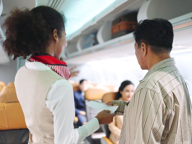 Flight attendant directing passenger to seat on plane