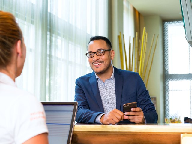 Traveler speaking to lounge front desk employee