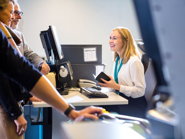 Airline employee checking documents at check-in desk