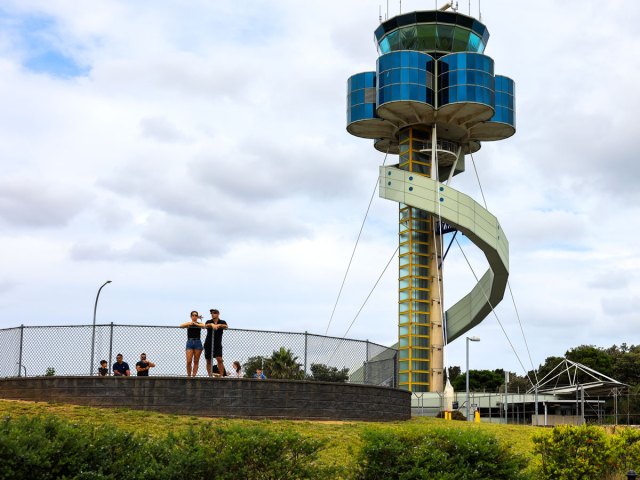 Enthusiasts wathcing planes under the control tower at Sydney Airport, Australia