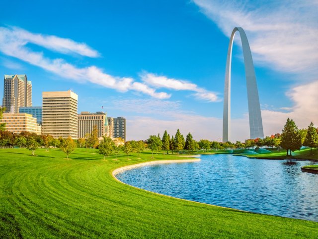 Gateway Arch towering above parkland and St. Louis skyline