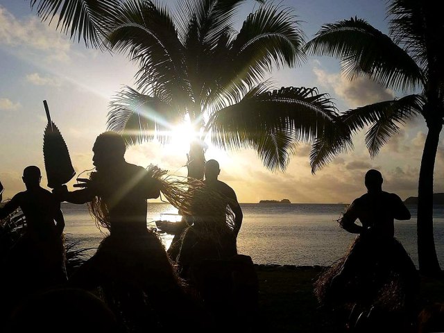 Traditional dance performance with palm trees and beach in background at Kokomo Private Island in Fiji