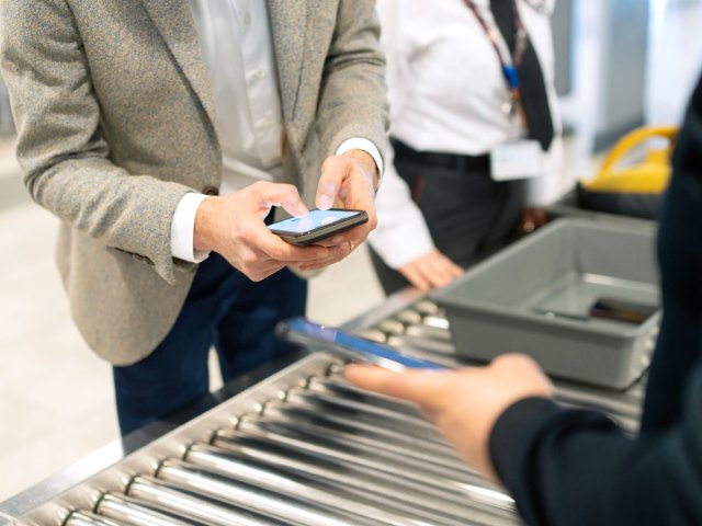 Traveler using smartphone at airport security checkpoint