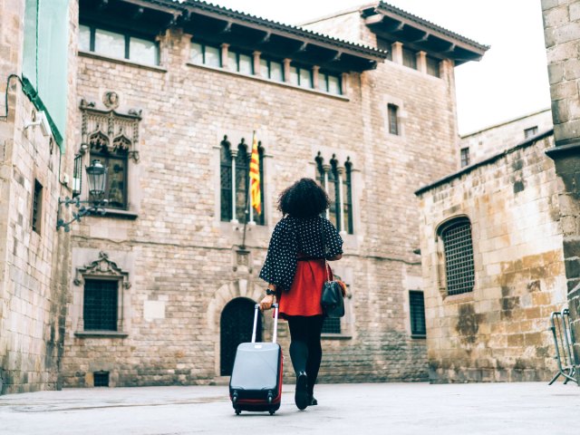 Tourist rolling suitcase through Gothic Quarter of Barcelona, Spain