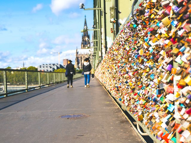 People strolling past padlocks attached to Hohenzollern Bridge in Cologne, Germany 