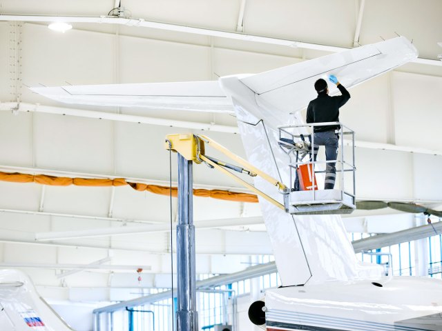 Technician painting aircraft tail in hangar